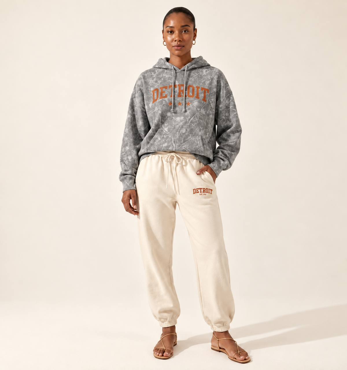 Grey camo Comfort Colors hoodie with arched rust Detroit wordmark and three stars, styled with ivory Detroit joggers