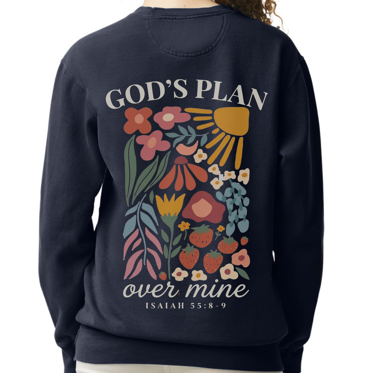 A person wearing a navy crewneck sweatshirt, showing the back graphic with the text 'GOD'S PLAN over mine ISAIAH 55:8-9' and a colorful floral illustration.